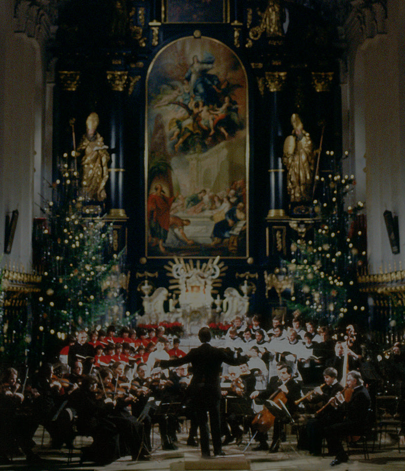 Banner für die Weihnachtsseite von DG, mit einem Orchester, das in einer Kirche spielt, mit Weihnachtsdekorationen.