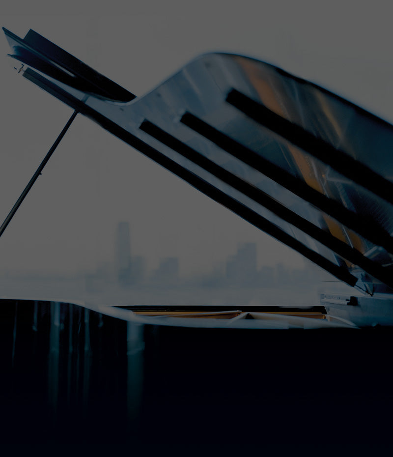 Schwarzes Piano vor Großstadt Skyline im fernen Hintergrund